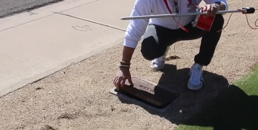 Technician using a ground microphone to locate an underground pipe leak