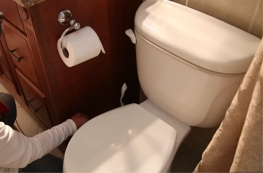 Technician inspecting plumbing around a toilet for a possible leak
